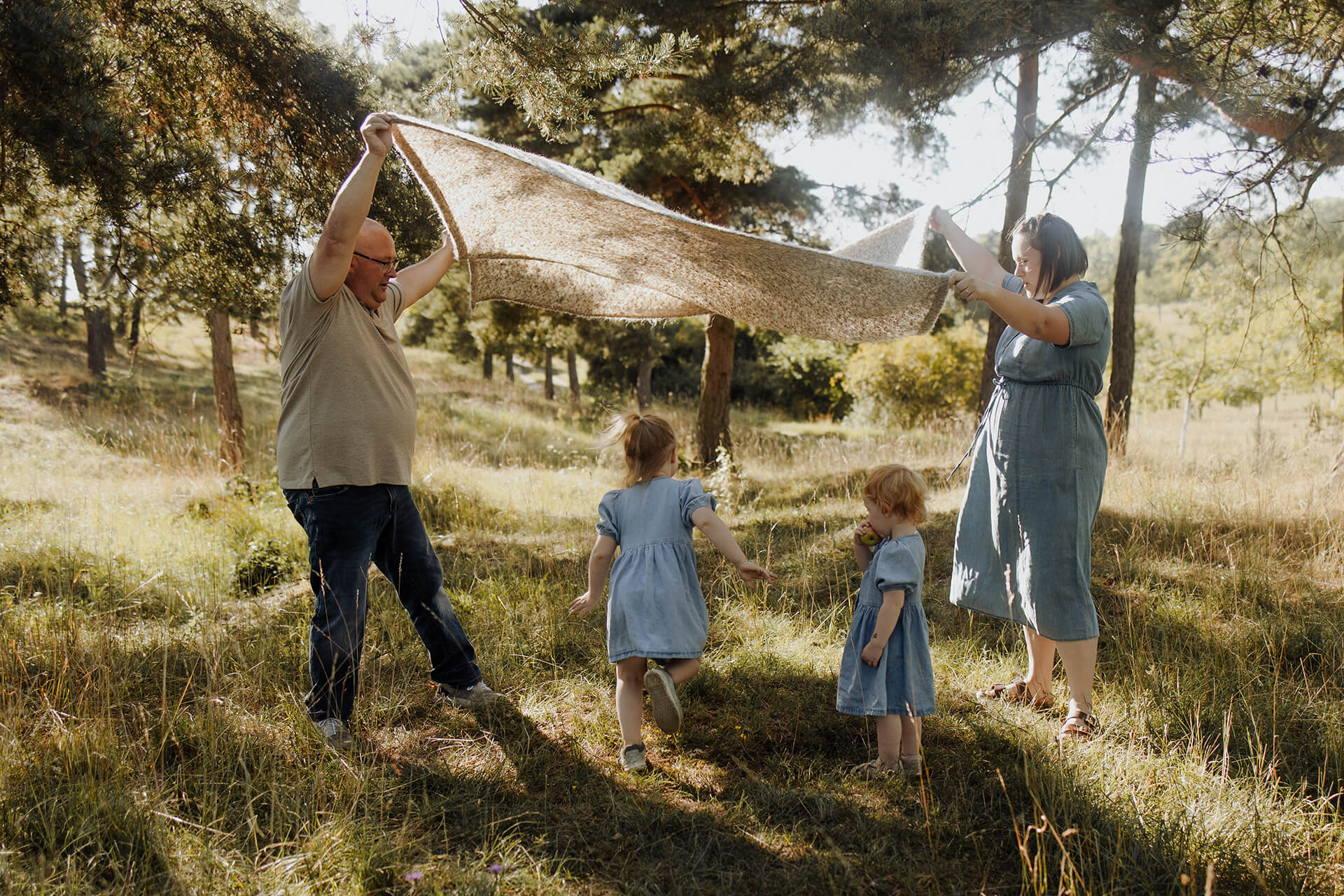 Eltern werfen Decke nach oben, Kinder rennen darunter