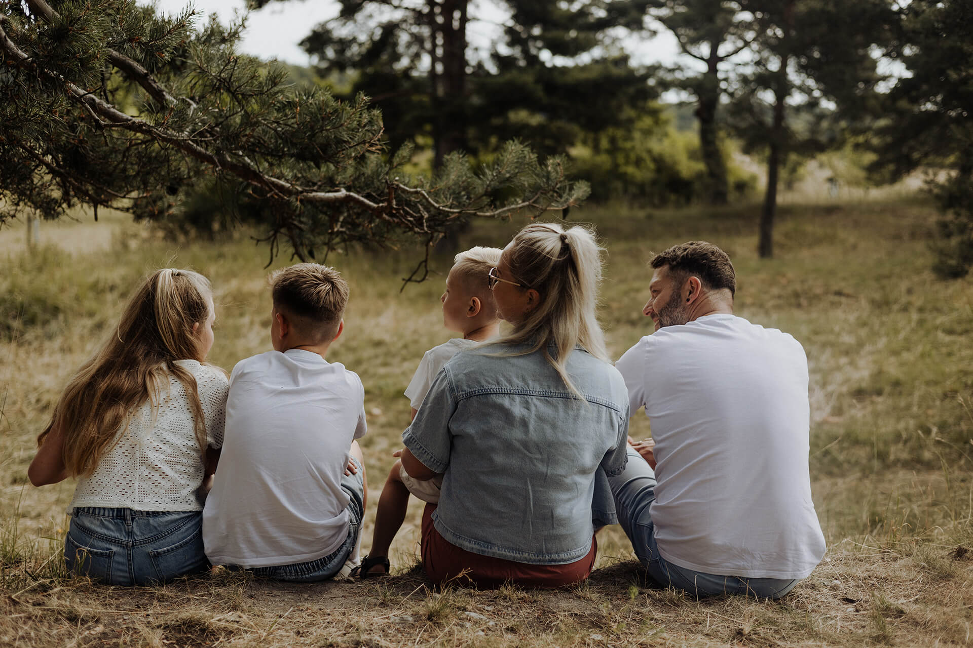 Familie sitzt am Waldrand eng zusammen