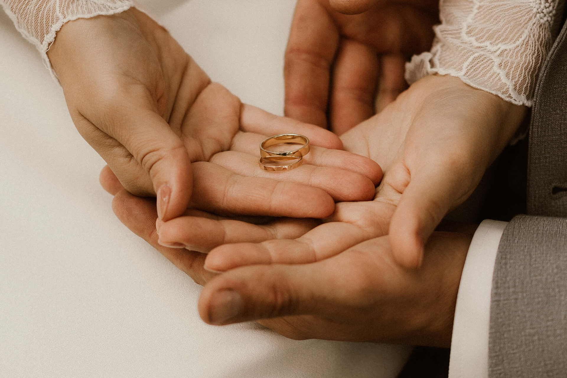 die Hände des Brautpaares sind übereinander in den Handflächen die Ringe