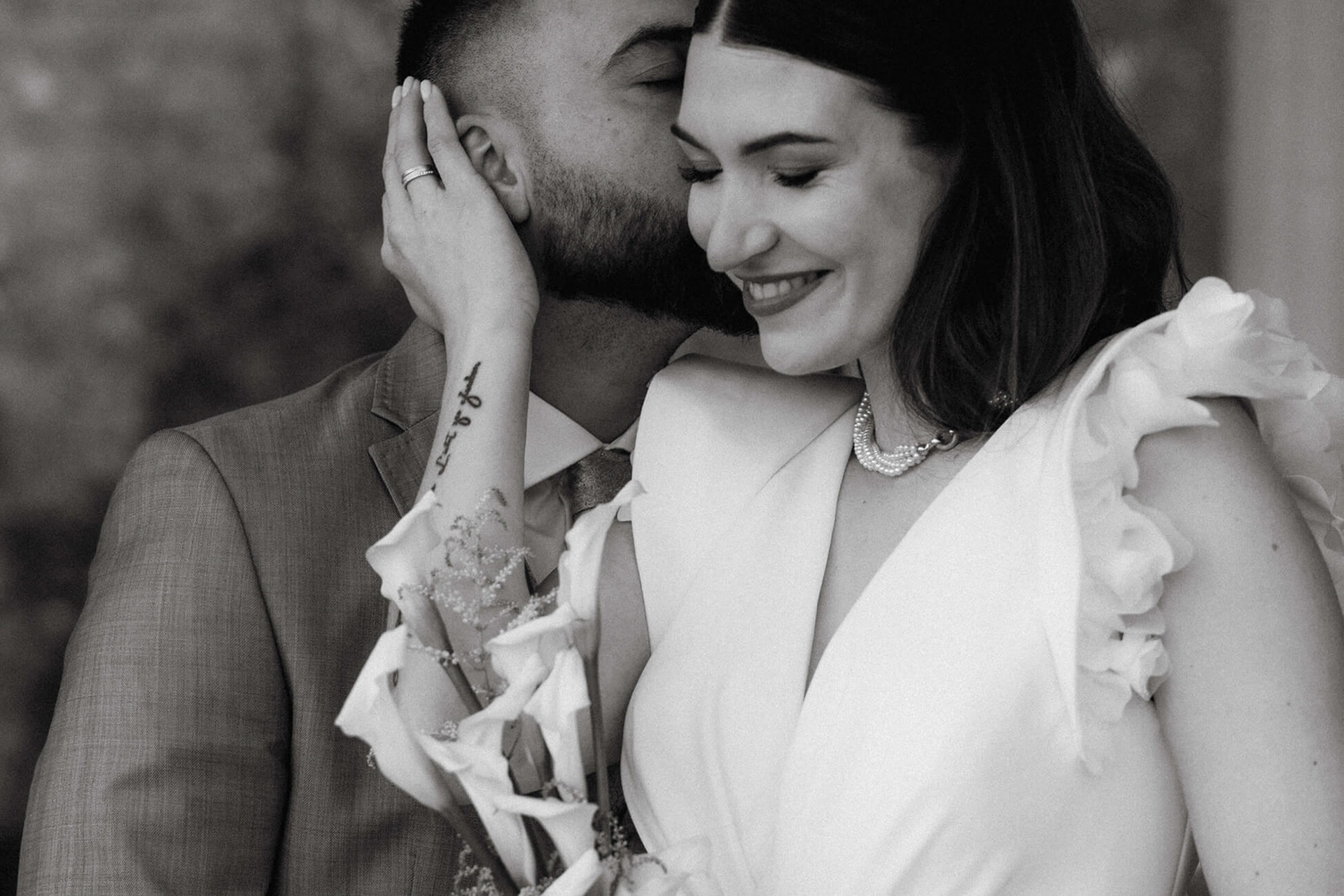 Bräutigam gibt Braut einen Kuss auf die Schläfe, Braut lächelt